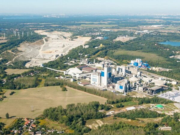 Panoramablick auf das Zementwerk Rüdersdorf mit Steinbruch, grüner Landschaft und Seen im Hintergrund. Das Bild symbolisiert nachhaltige Industrie im Einklang mit der Natur.