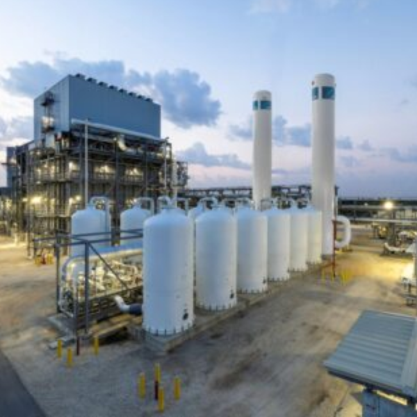 Industrieanlage mit weißen Tanks und Rohrsystemen unter freiem Himmel, Teil einer modernen Gas- oder Chemiefabrik.